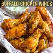 A parchment paper lined basket with a stack of buffalo wings in the front and a small bowl of ranch in the back with the words Air Fryer Buffalo Chicken Wings at the top.
