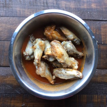 Chicken wings in a bowl with buffalo sauce.