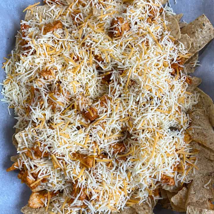 Cheese and buffalo chicken on top of tortilla chips.