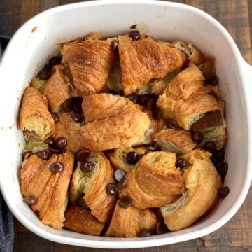 A white baking dish with baked chocolate croissant bread pudding.
