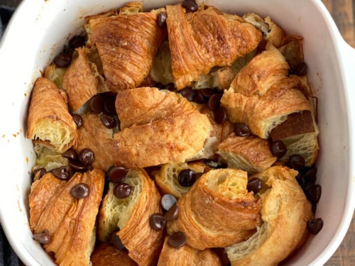 A white baking dish with baked chocolate croissant bread pudding.
