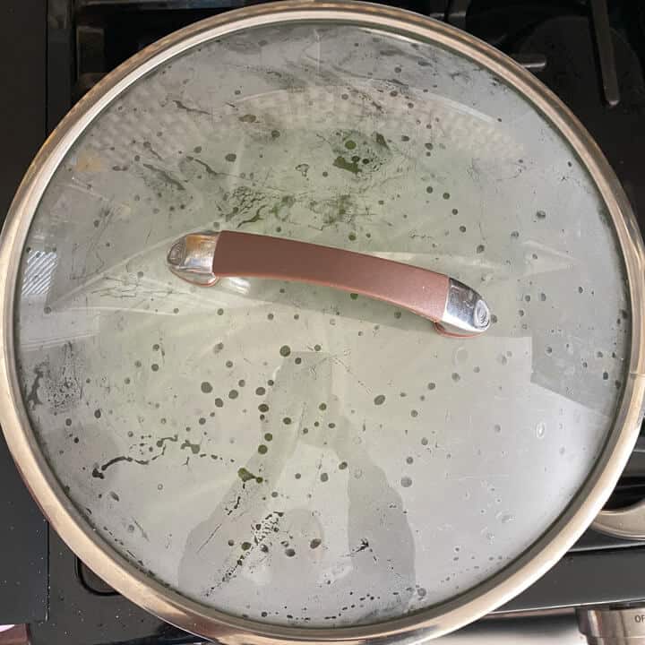 A covered skillet cooking the green beans.
