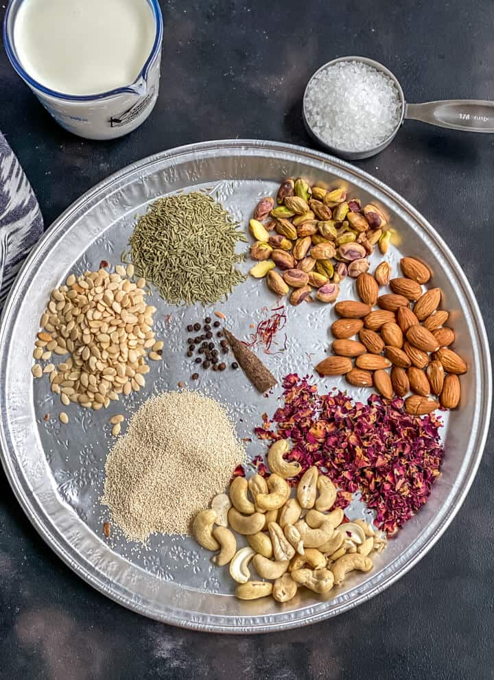 A silver platter with nuts, seeds, and spices used to make thandai.