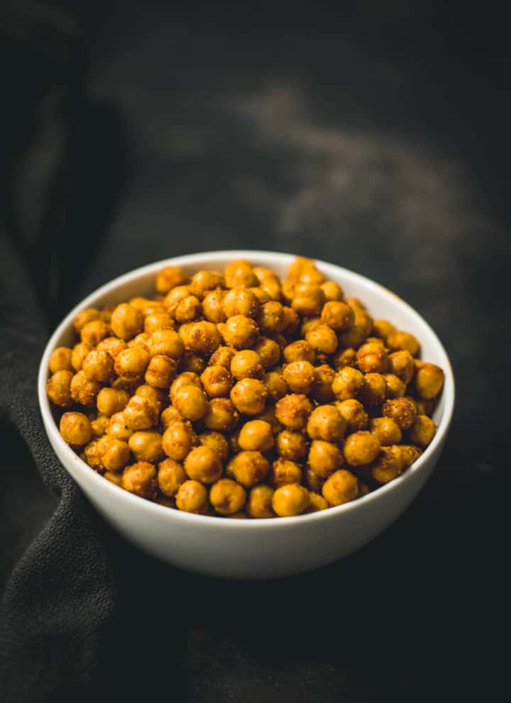 A white bowl with air fryer roasted chickpeas on a black towel.