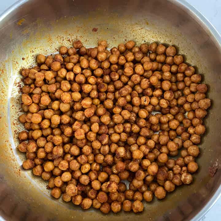 Fully seasoned chickpeas in a bowl coated with oil and spices.