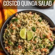 A black bowl filled with quinoa salad and topped with two limes and the words Easy Costco Quinoa Salad at the top.