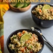 Two small black bowls filled with quinoa salad with a spoon in between the bowls and the words Favorite Instant Pot Quinoa Salad at the top.