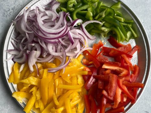 A plate with sliced peppers and red onion.