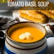 A small soup bowl with a handle on the right side filled with tomato basil soup and topped with oyster crackers with a grilled cheese sandwich in the back and the words Instant Pot Tomato Basil Soup at the top.