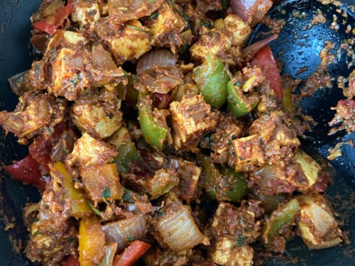 Paneer added to the wok with a spoon to the right.