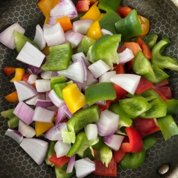 Bell pepper and onion in a wok cooking.