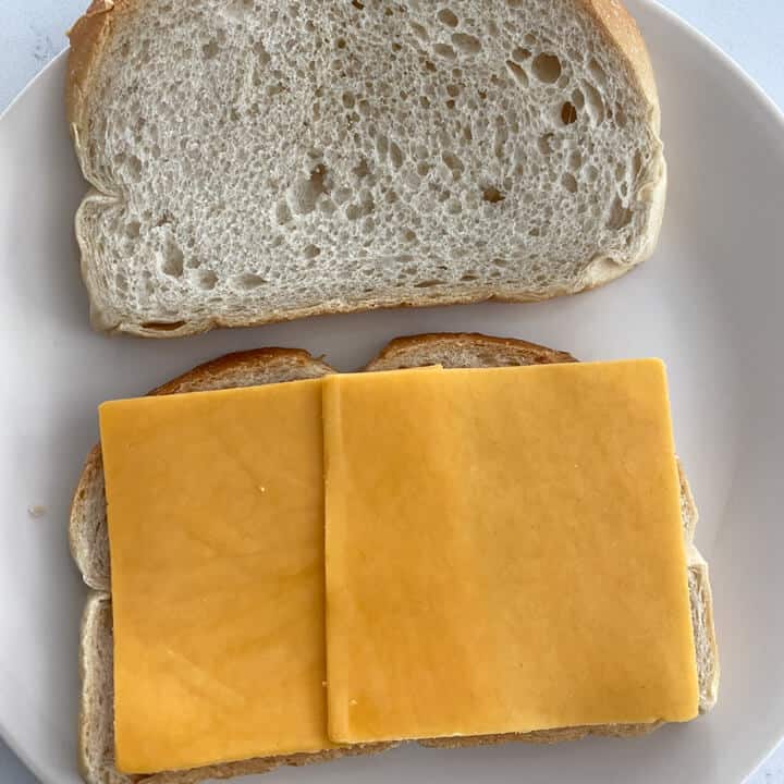 Two slices of cheddar cheese on a slice of bread