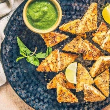 sesame grilled paneer served on a black plate with chutney