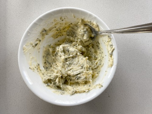 Mixing together butter with herbs to make a garlic butter.