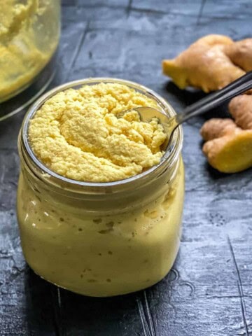 A jar of ginger paste with a spoon in it.