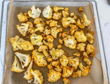 A tray of cauliflower, lined with parchment paper.