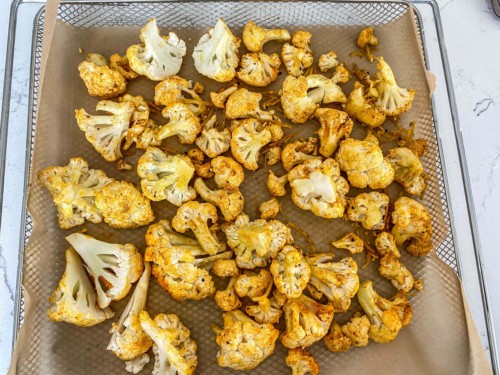 A tray of cauliflower, lined with parchment paper.