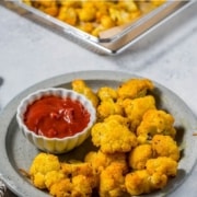 A plate of cauliflower florets with a side of ketchup.