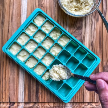 Filling a silicone ice cub tray with minced garlic.