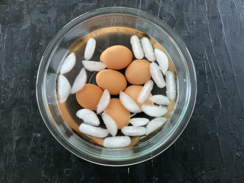 A glass bowl of ice water with air fryer hard boiled eggs