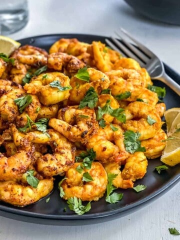 A plate of cooked shrimp, garnished with lemon and parsley.