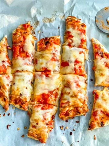 A small cheese pizza, cut into strips with a pizza cutter.