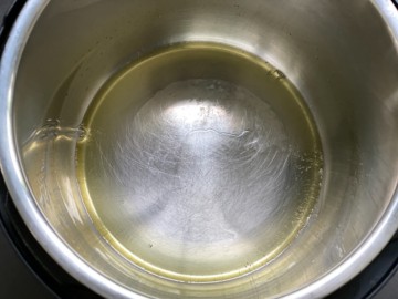 An Instant Pot with heated ghee in the inner pot.