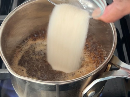 Adding tea and sugar to boiling water.