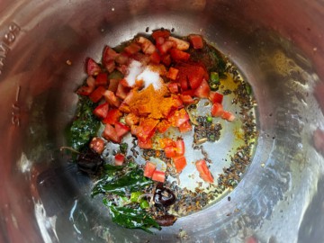 Adding tomatoes and aromatics to an Instant Pot with tempering seeds.