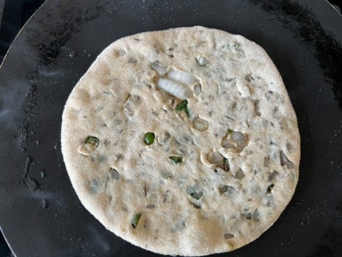 Cooking paratha until small bumps form.