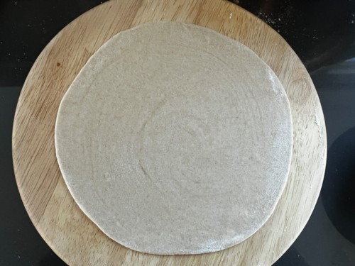 Rolling paratha into a round shape.