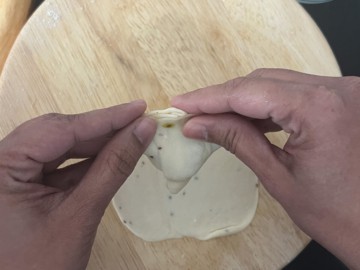 Pressing along the edges to seal a samosa.