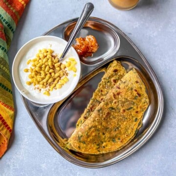 A stainless plate with folded paratha.