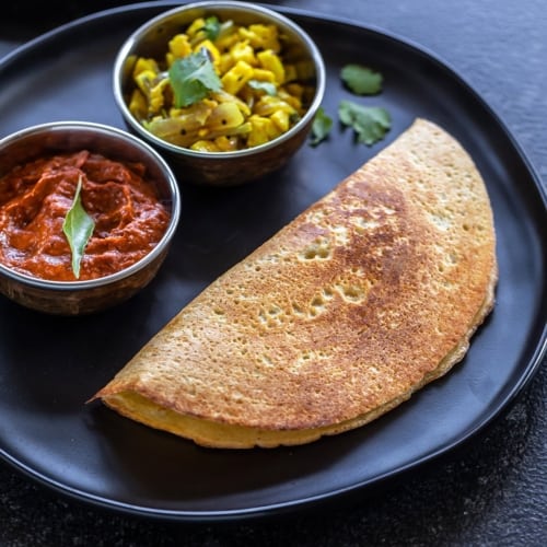 Moong dal dosa served with chutney and a vegetable dish