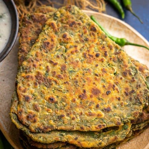 Palak paratha served on a brown plate and chutney