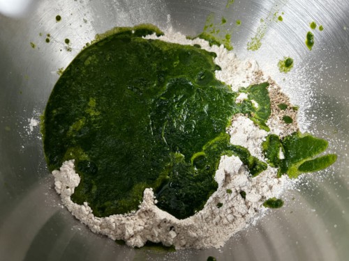 Blended spinach puree added to metal bowl with whole wheat atta flour.
