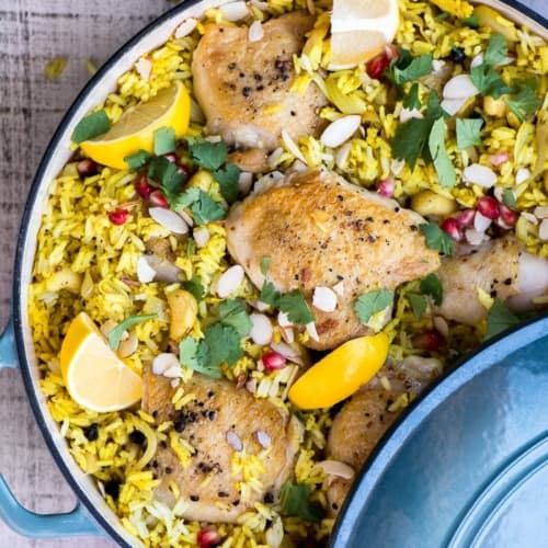 Chicken biryani served in a blue casserole topped with lemon slices