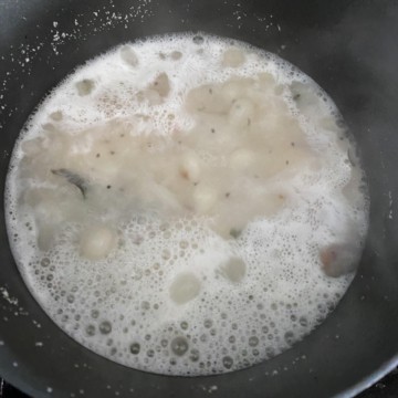 Hot water to rava / suji mixture in a black non-stick wok