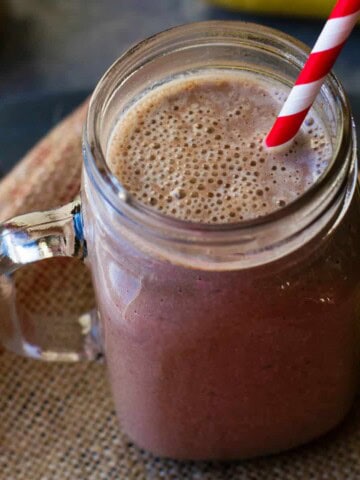 chocolate almond smoothie in a mason jar with straw on a burlap napkin