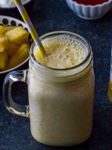 Pineapple orange smoothie served in a ball jar with a straw