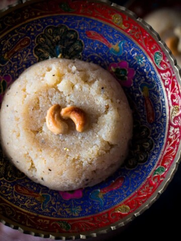 Sooji halwa topped with nuts served in a red and blue bowl