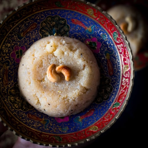 Sooji halwa topped with nuts served in a red and blue bowl