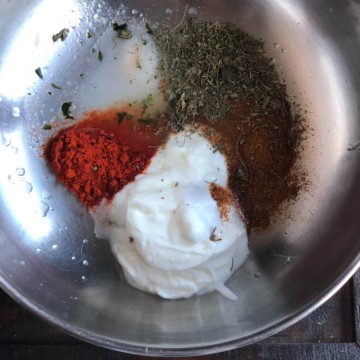 yogurt, chili powder, garam masala and other spices in a steel bowl