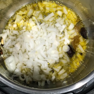Onions being added to a tempering of spices